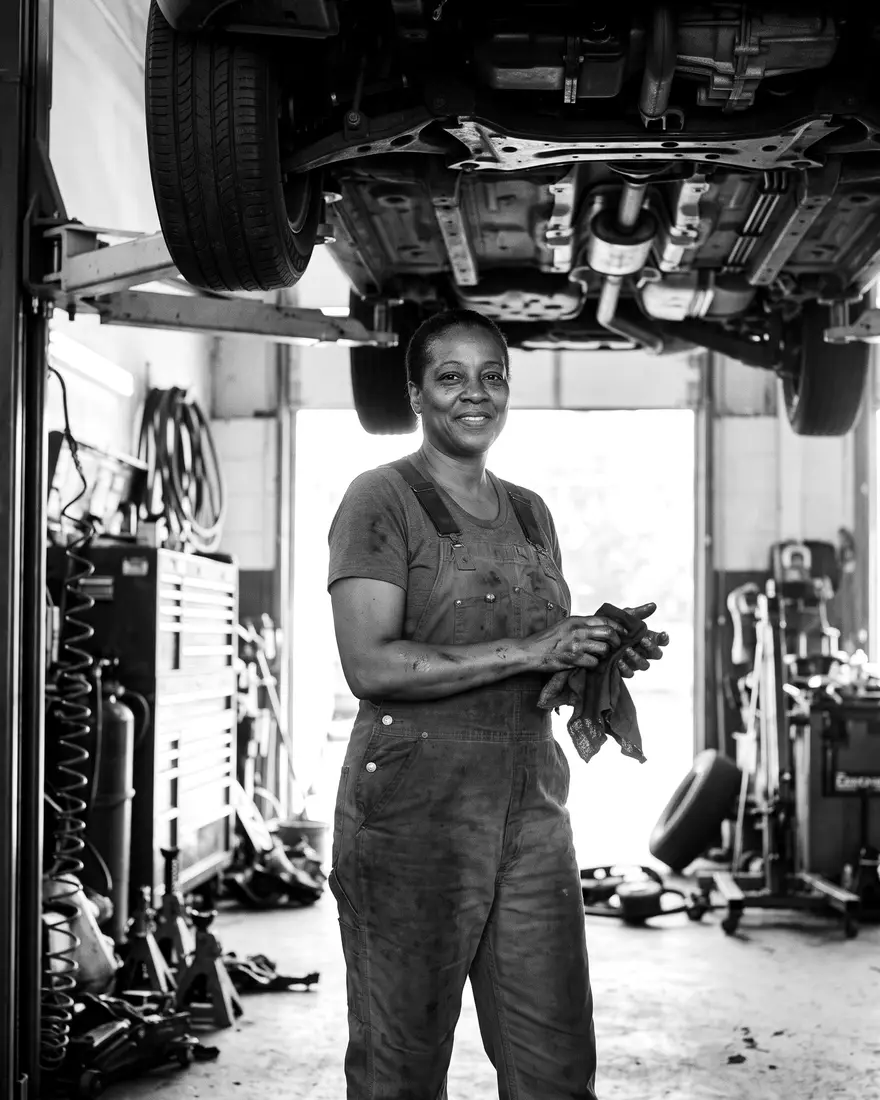 The owner of a family auto repair shop wiping her hands under a car lift